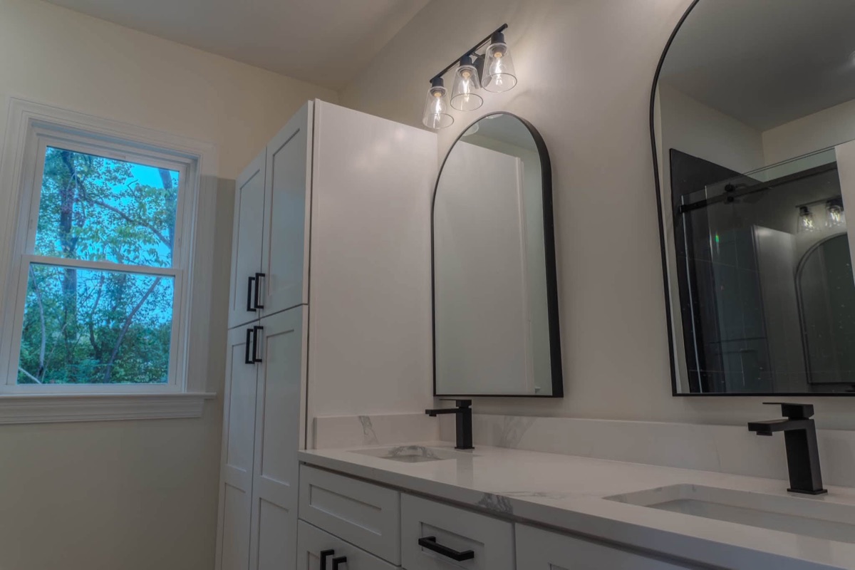 Finished bathroom with a double vanity and arched mirrors